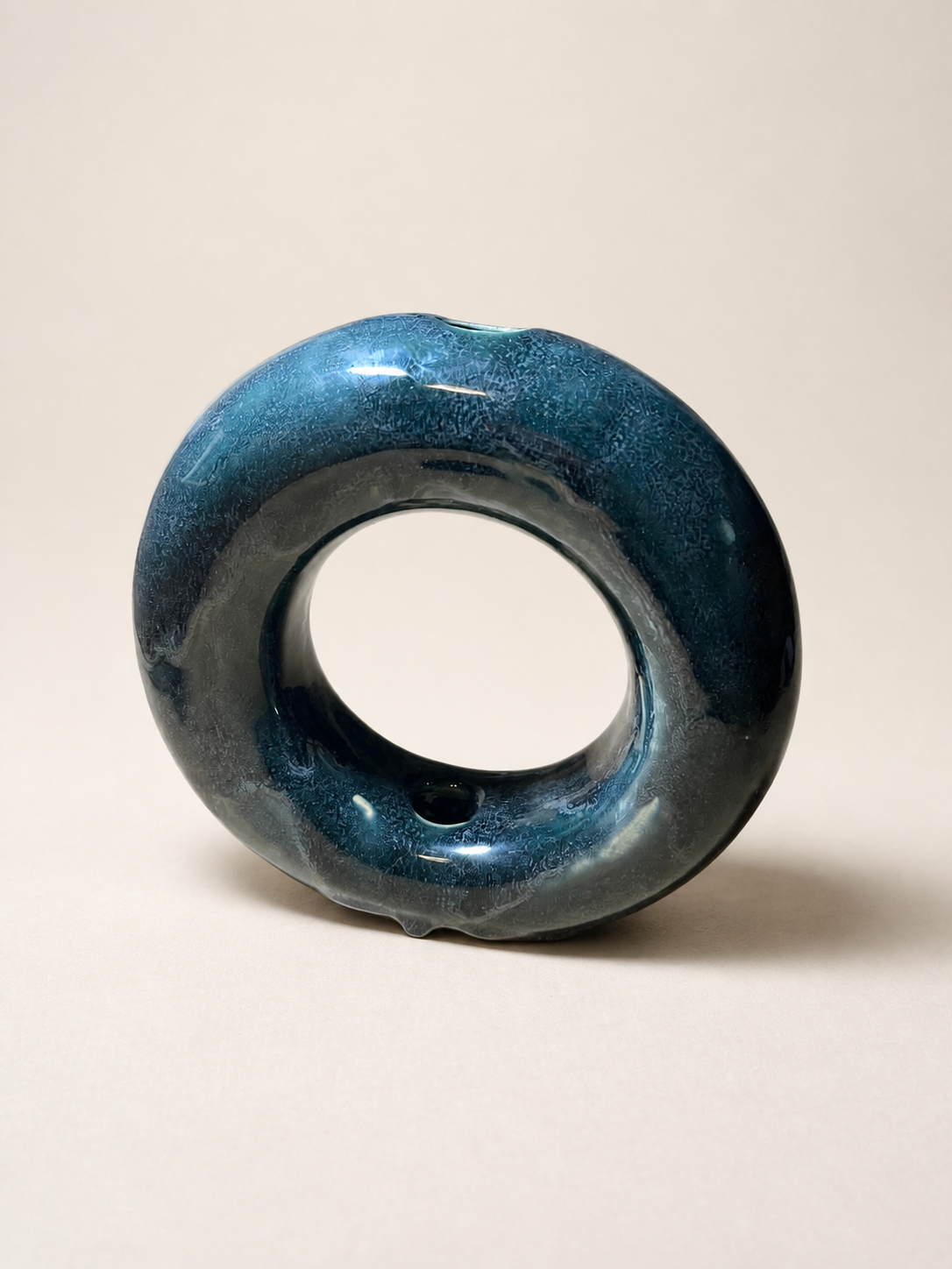 A dark blue ceramic donut vase.