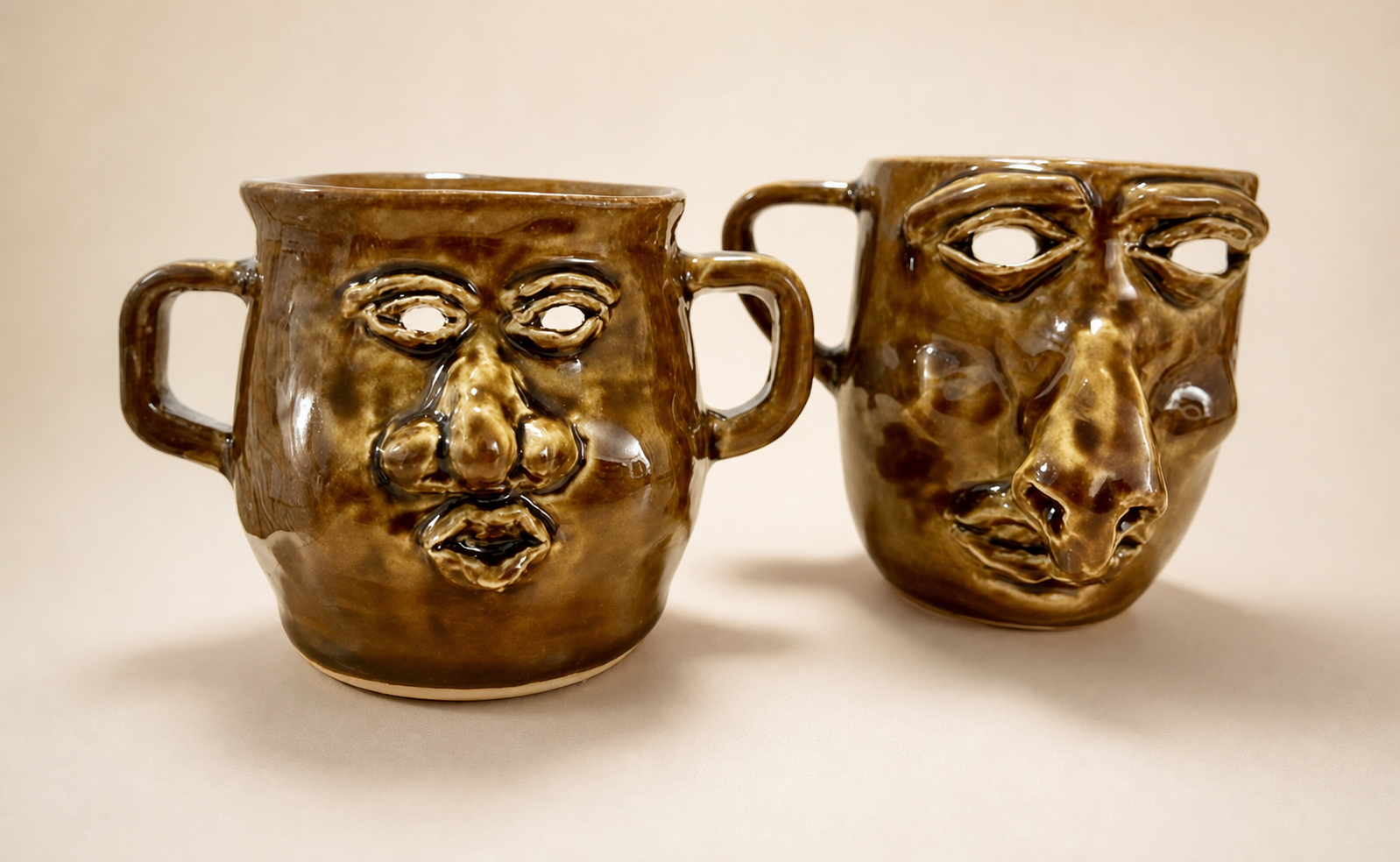 Two ceramic mugs with expressive faces.