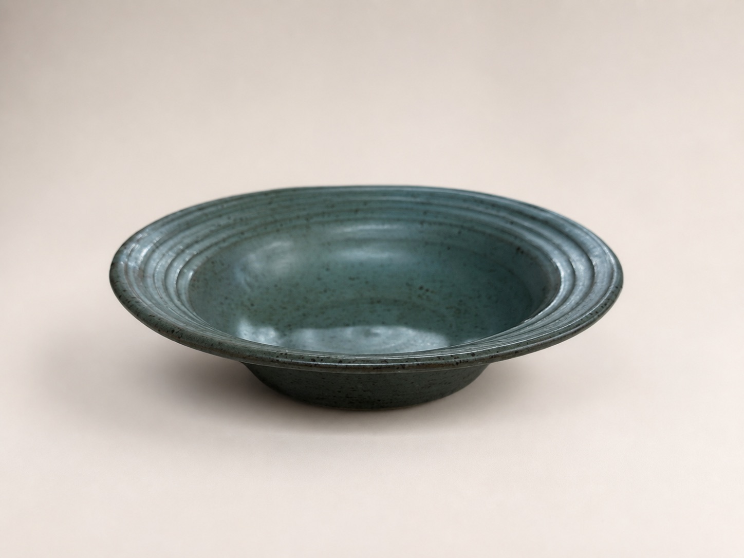 A shallow teal bowl with a broad ridged rim.