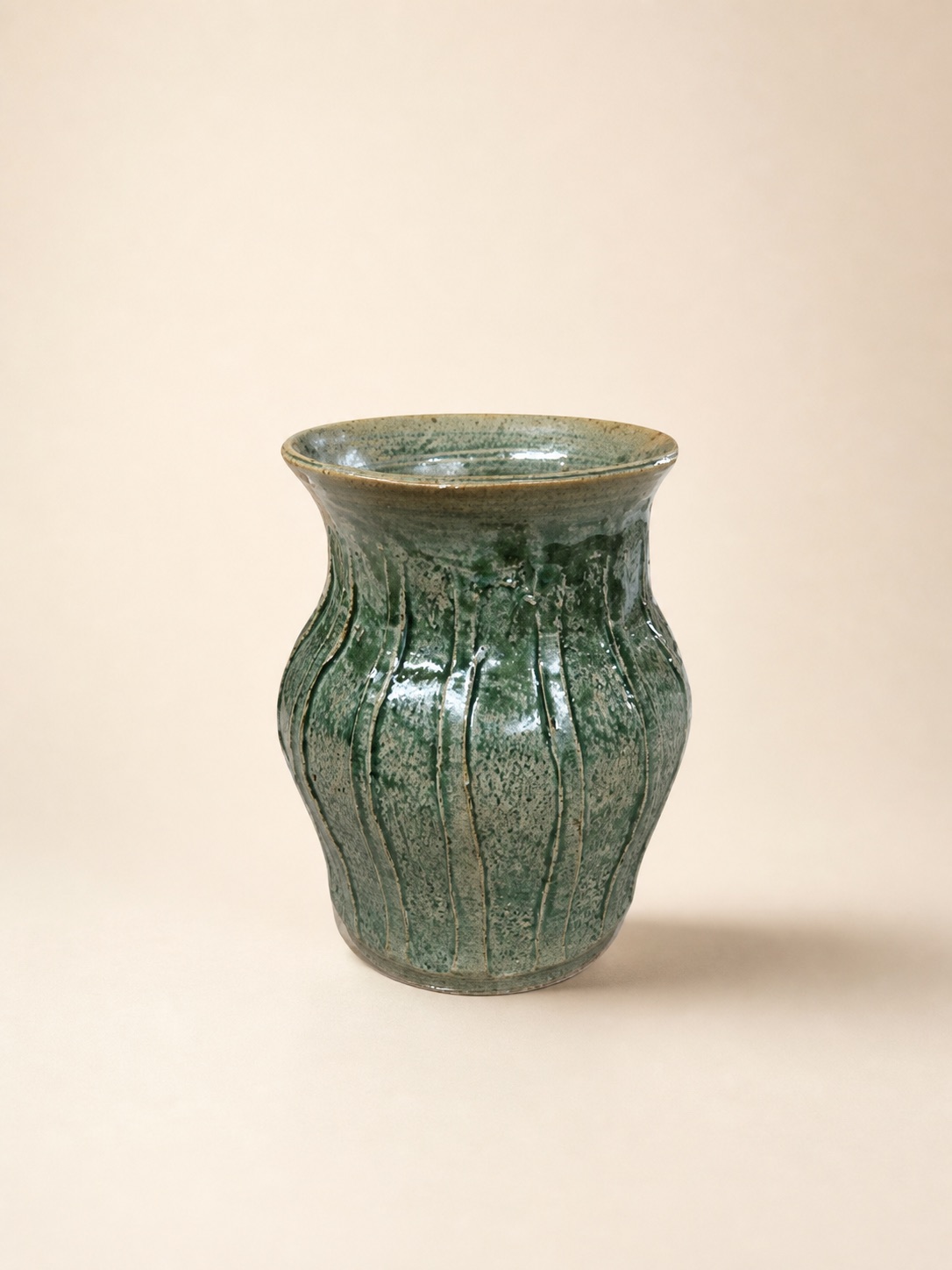A green fluted vase with a gently flared rim.
