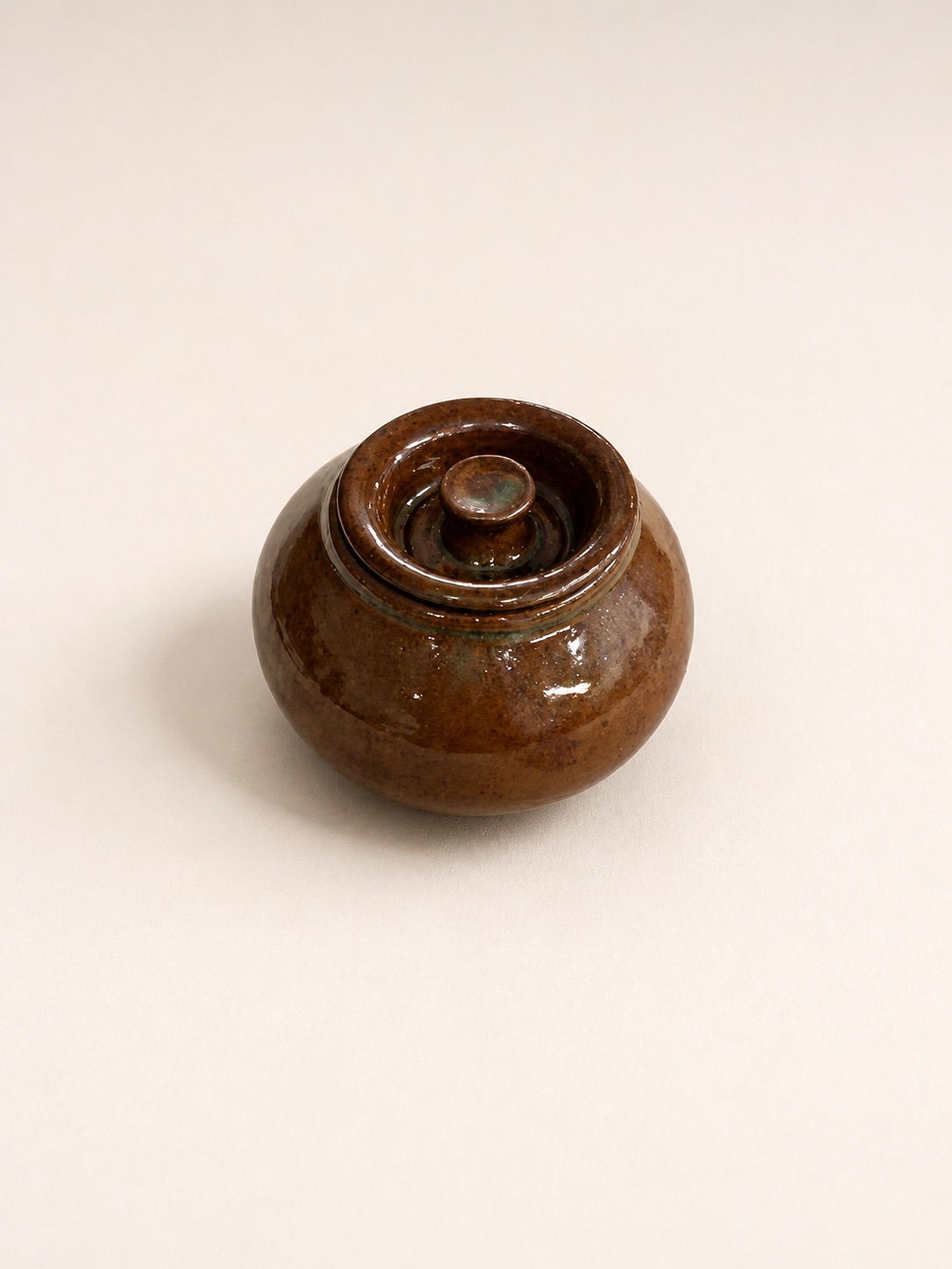 A small round brown lidded vessel.