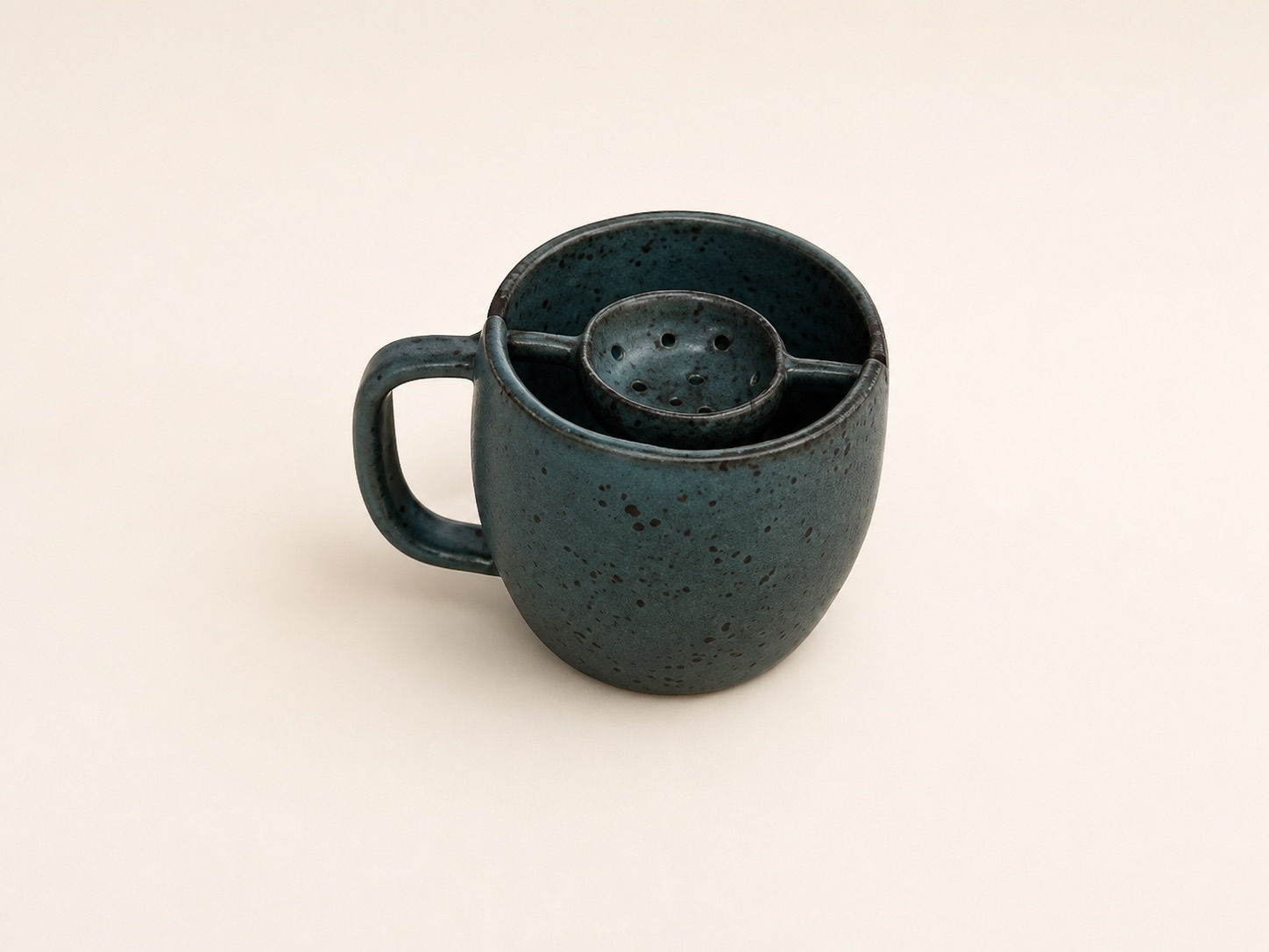 A dark teal mug with a fitted ceramic infuser.