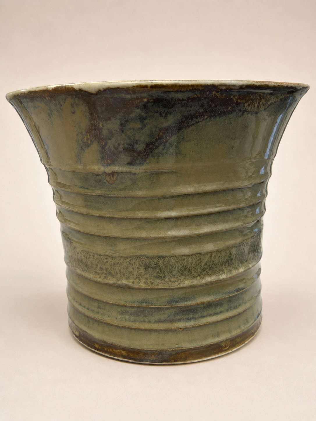 A large olive-glazed vessel with raised horizontal bands.