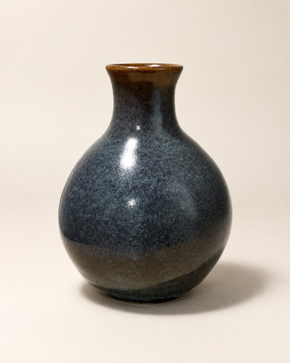 A round charcoal-blue bottle vase with warm iron-brown glaze.