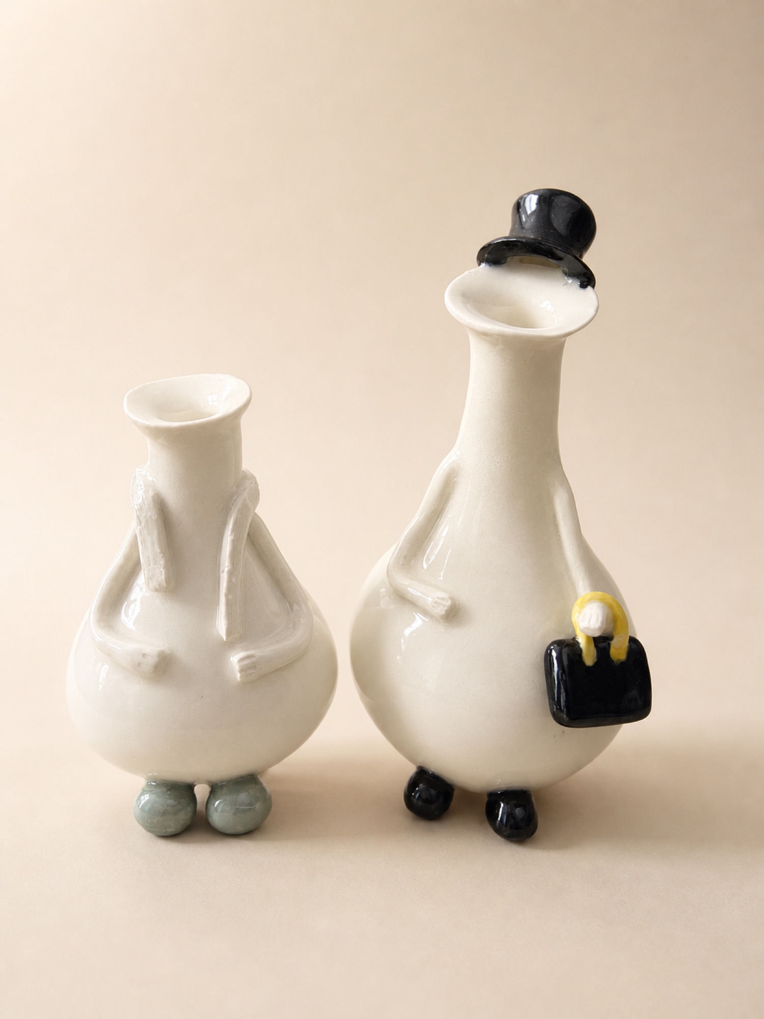 Two cream Azorks, one wearing a black top hat and carrying a handbag.