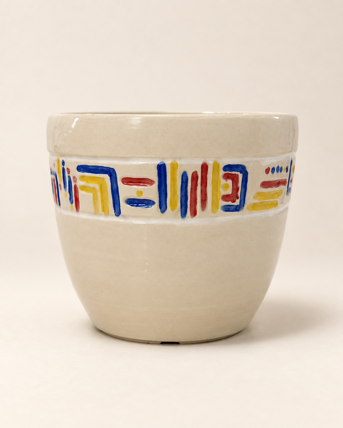 A large cream ceramic pot with a band of red, blue, and yellow geometric lines.